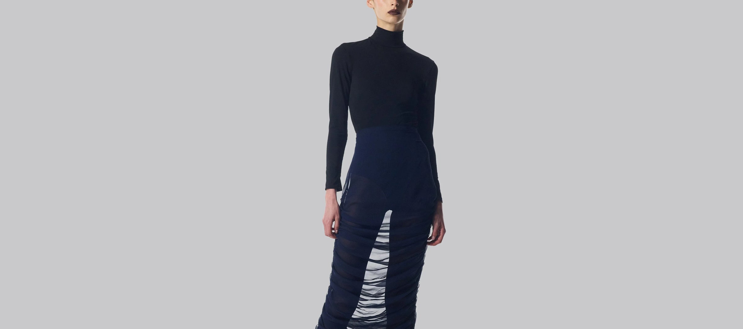 Black long-sleeved dress with sheer ruched skirt.