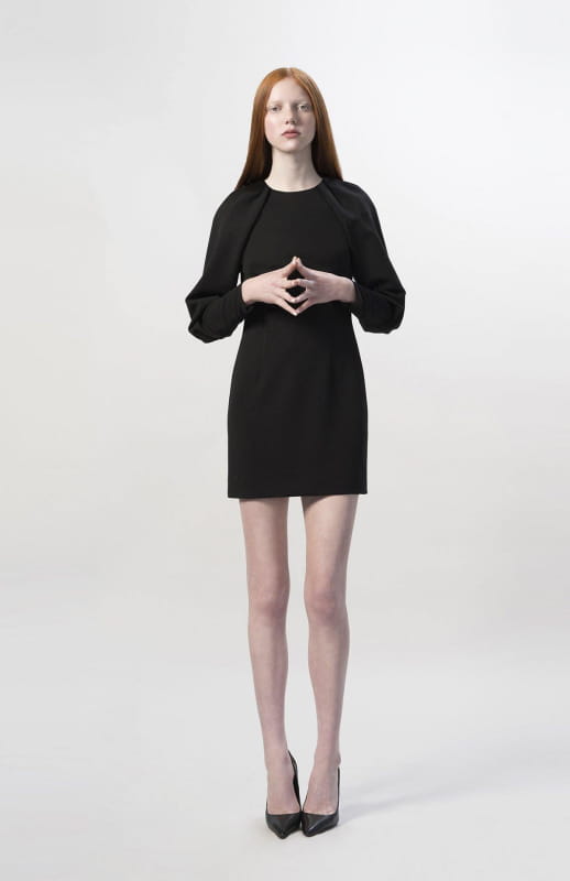 A one-off piece and the perfect little black dress. This is a short backless style with oversized draped sleeves and closed neck with pleated detailing.