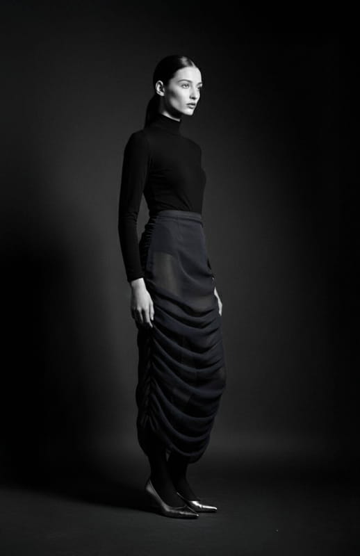 model is wearing black turtleneck top and silk draped skirt