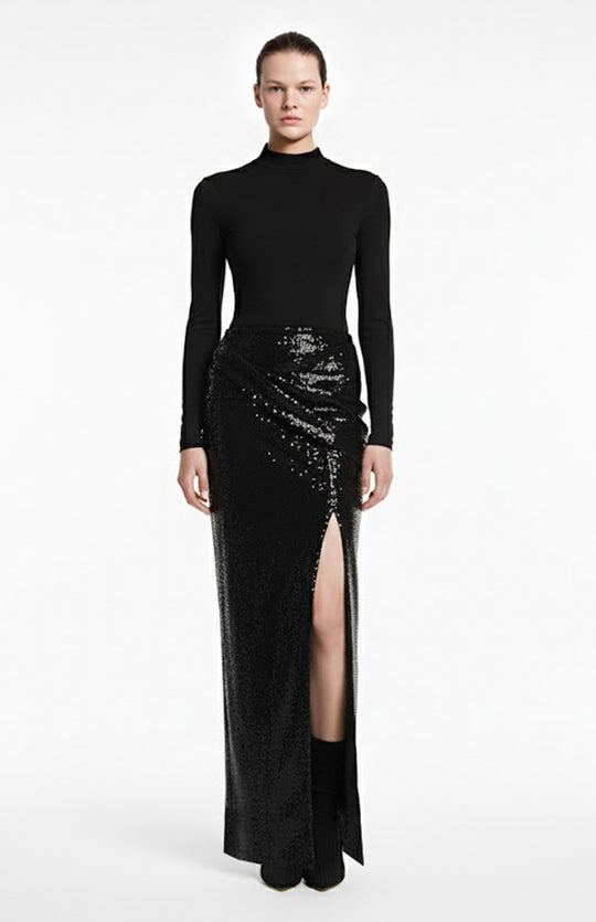 model wearing black turtleneck and long black draped sequin skirt with a slit