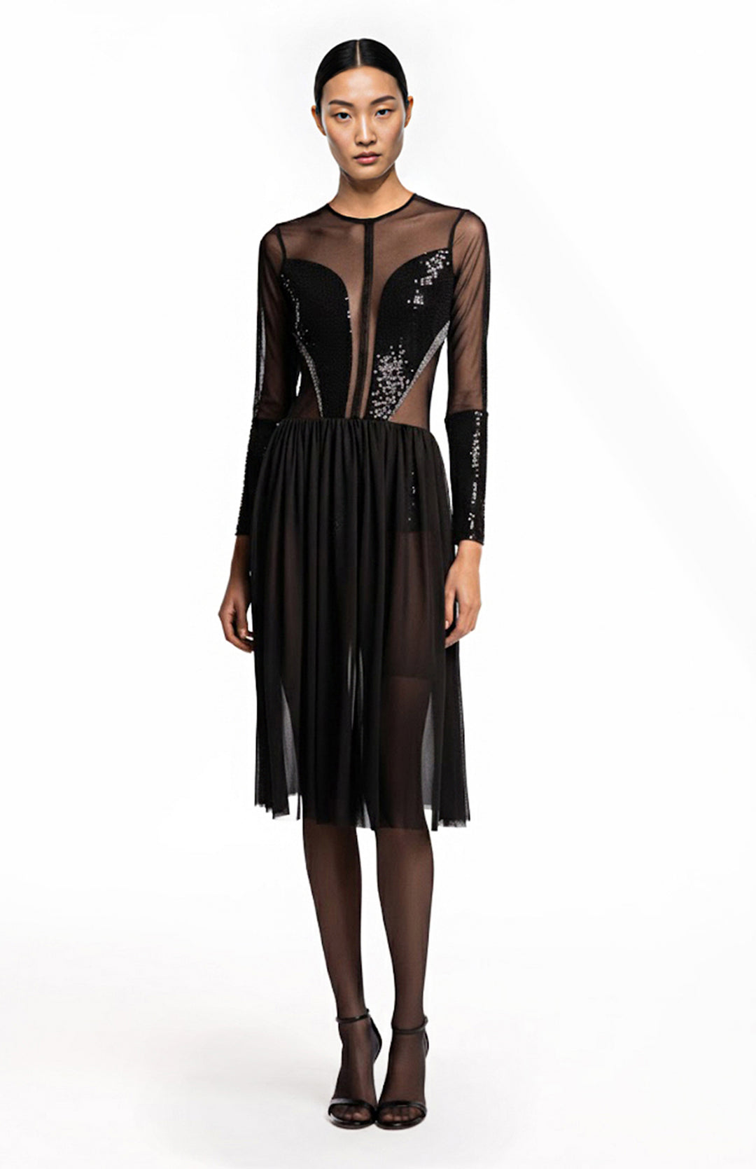 Model wearing a sheer black cocktail dress with sleeves