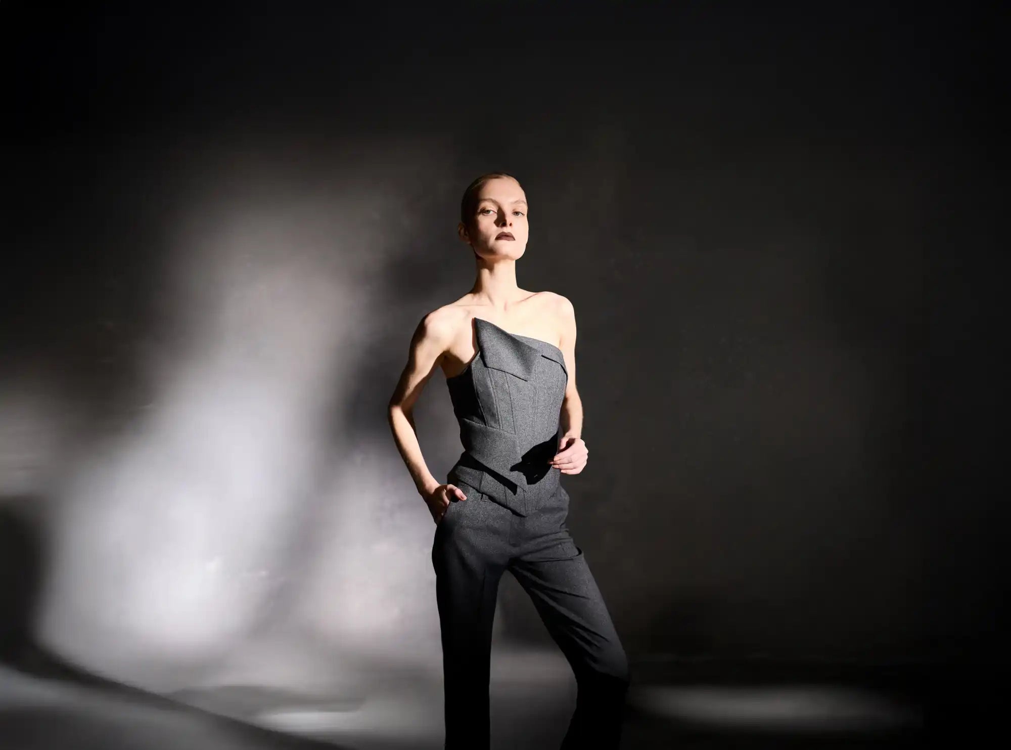 A woman in an asymmetrical gray strapless top and matching pants.