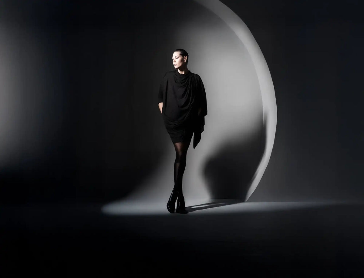 Woman in a black tunic dress, opaque tights, and high heels.
