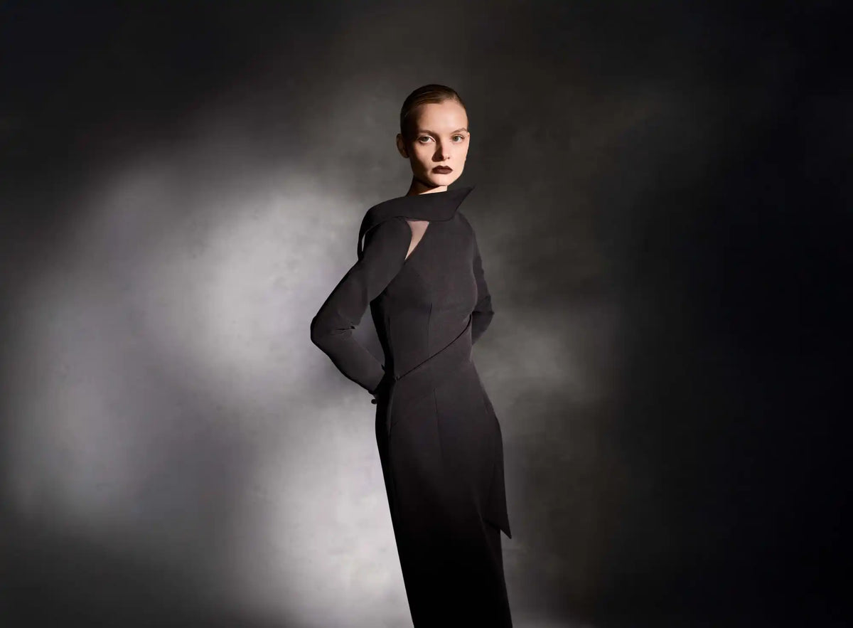 A woman in a dramatic black evening gown with sculptural details.