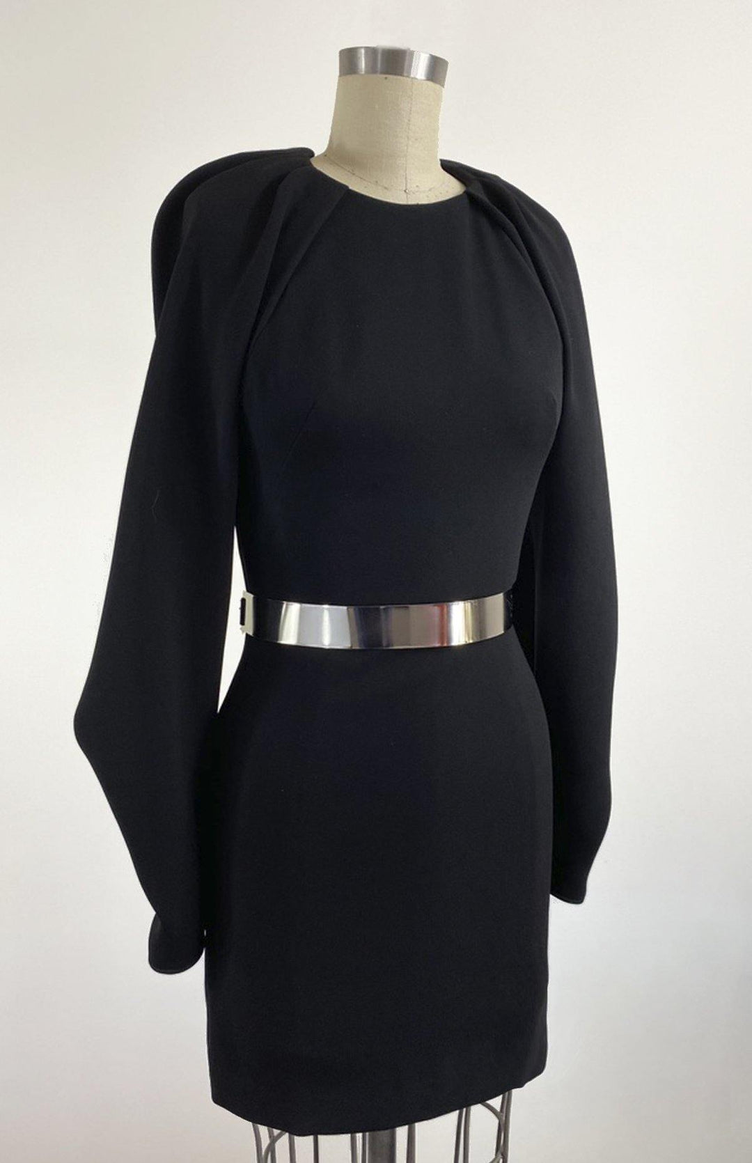 A one-off piece and the perfect little black dress. This is a short backless style with oversized draped sleeves and closed neck with pleated detailing.