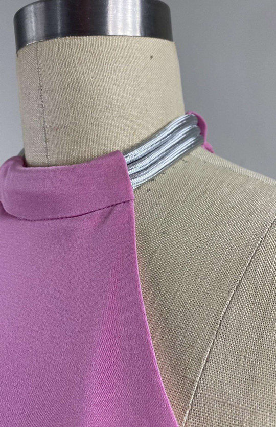 Detail of pale pink and fuschia long, sleeveless, colorblock dress in double silk crepe with a futuristic silver neck trim detail.