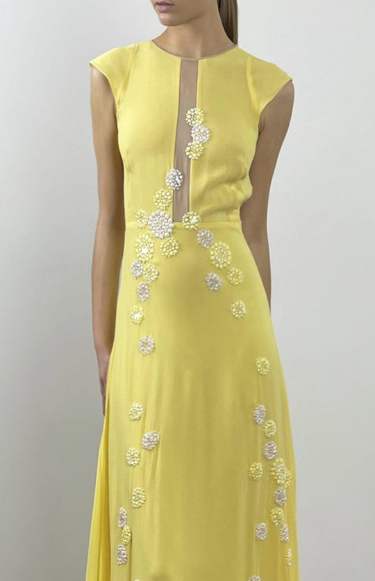close up of Yellow, sleeveless, long evening dress with sheer, nude panels, hand applique lace embellishment and long train.